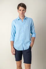 Camisa celeste de lino con cuello clásico y manga larga. Presenta un pequeño logo bordado en el pecho.