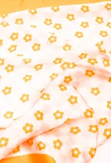 Pañuelo cuadrado con estampado de flores sobre fondo rosa y cuadros.