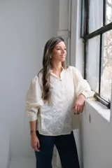 Blusa color crema con bordado calado, cuello mao y mangas largas abullonadas.
