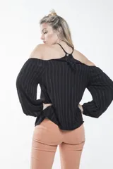 Blusa negra con mangas largas abullonadas, hombros descubiertos, cuello halter cruzado y bordado floral en el pecho.