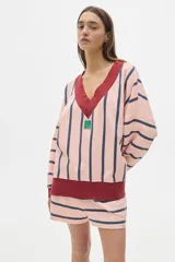 Buzo de algodón lavado a rayas rosas y azul marino, de fit oversized, manga larga y hombros caídos. Cuello en V, terminaciones a contratono y parche en el frente.