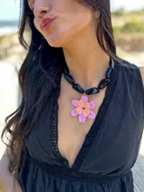 Collar corto con cuentas grandes negras y dije de flor con pétalos lilas y centro naranja.