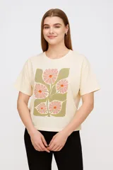Remera color crema con estampado de flores rosadas y hojas verdes.