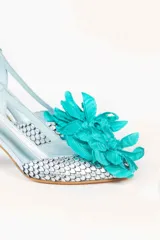 Zapato de tacón plateado con diseño de escamas y flor turquesa en la punta.