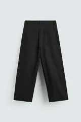 Pantalón negro de corte amplio, tipo balloon fit, con pinzas en la cintura, bolsillos laterales y traseros de ojal.