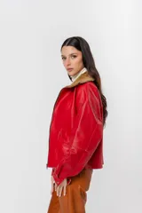 Chaqueta bomber de cuero color marrón, con cuello de piel sintética roja, cierre frontal con cremallera y bolsillos laterales.