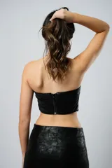 Top strapless negro de cuero sintético con corte irregular en el ruedo.
