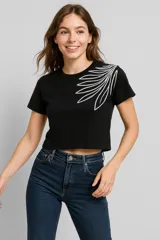 Remera cropped negra de algodón con cuello redondo y estampado de hojas blancas en el hombro.