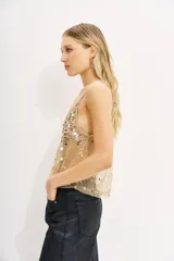 Top de tul negro, transparente, con escote en V ribeteado en satén negro y bordado a mano con lentejuelas y cuentas en tonos dorados, plateados y blancos. Posee breteles finos regulables.