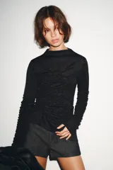 Top negro de cuello perkins y manga larga con frunces en el pecho y las mangas.