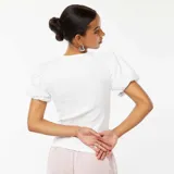 Camiseta blanca de punto con cuello redondo y mangas cortas abullonadas.