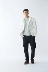 Campera de felpa color beige con cierre frontal, capucha con cordón ajustable, bolsillos laterales y logo estampado en el pecho.