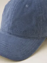 Gorra de béisbol azul de pana con visera curva y orificios de ventilación bordados.