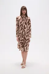 Vestido camisero midi holgado con estampado animal print tipo cebra en negro y beige. Presenta cuello camisero, botones frontales y mangas largas con puños abotonados.