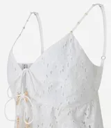 Blusa cropped blanca de algodón con bordado floral, breteles finos y escote en V con lazo frontal.