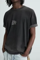 Camiseta negra de corte holgado, cuello redondo y manga corta. Estampado frontal con texto en blanco y parche rectangular en la espalda. Efecto lavado.
