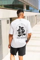 Remera blanca de algodón con estampa en la espalda que incluye texto y diseño de hojas.