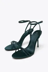 Sandalias de tacón alto color verde oscuro, con tiras finas en la parte delantera y cierre de hebilla ajustable al tobillo.