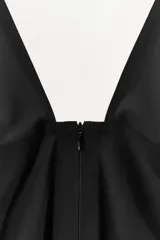 Mono largo negro, de corte ajustado, con escote pico pronunciado y tirantes anchos. Presenta un cierre frontal con cremallera oculta.