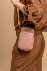 Bandolera pequeña tipo 'phone bag' de símil cuero color rosado pálido, con cierre de cremallera y correa ancha de tela con diseño de chevron en tonos claros.