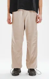 Pantalón beige de corte sastrero con bolsillos laterales, estilo holgado y tela suede. Cintura trasera con doble ajuste elástico y tanca, cintura delantera con botón y cierre.