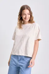 Camiseta de manga corta color crudo con apliques bordados en relieve con forma de flor en toda la prenda.