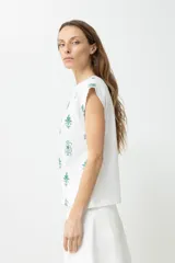 Blusa blanca de mangas cortas con bordado floral en el frente.