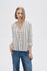 Camisa holgada de viscosa con estampado de rayas verticales en blanco y negro, cuello en V y mangas 3/4 con detalle de botones.