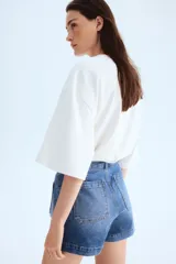 Short de denim de algodón levemente elástico con bolsillos parche delanteros y traseros. Modelo de tiro alto con cierre y botón.