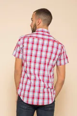Camisa de manga corta con estampado a cuadros en tonos azul, rojo y blanco. Cierre con botones y tela ligera.