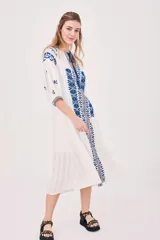 Vestido túnica blanco con bordados azules, mangas 3/4 y cuello con lazo ajustable.