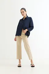 Camisa color beige de corte amplio, con cuello clásico, manga larga y bolsillo en el pecho.