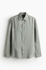 Camisa de lino color gris con cuello inglés, tapeta clásica, canesú en la espalda, mangas largas con tapeta de manga y botón, cierre ajustable de botón en los puños y bajo redondeado.