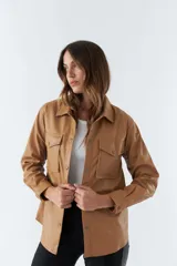 Sobrecamisa color marrón de poliuretano, con cuello clásico, cierre frontal con botones a presión, mangas largas con puños abotonados, dos bolsillos tipo parche con solapa y botón en el pecho.