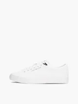 Zapatillas de corte bajo confeccionadas en una mezcla de piel y materiales sintéticos, color blanco. Presentan un diseño atemporal con cordones al tono, suela de goma vulcanizada y detalles distintivos de la marca Tommy Hilfiger, incluyendo el logo en el lateral, la lengüeta y el talón.
