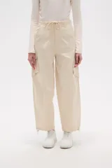 Pantalón cargo de jean color beige, de calce bajo, con bolsillos laterales y cordón ajustable en la cintura.