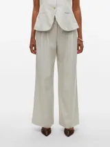 Pantalón sastrero de corte wide leg color beige, tiro medio, con bolsillos laterales, presillas para cinturón y detalle de pliegues en el frente.