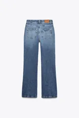 Pantalón de jean azul de tiro alto, corte bootcut, con cinco bolsillos, cierre frontal con cremallera y botón.