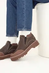 Bota de cuero color marrón chocolate, con cierre frontal con cremallera, costuras en contraste y suela track.