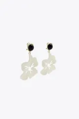 Aros colgantes con forma de flor color crema y botón negro en la parte superior.
