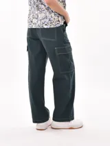 Pantalón cargo de mujer color beige claro, tiro medio/alto, corte ancho y recto, con bolsillos laterales tipo parche en las piernas.