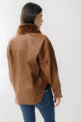 Campera corta de cuero color marrón con cuello de piel sintética color marrón claro, cierre frontal con botones a presión, mangas largas y bolsillos con solapa en el pecho.