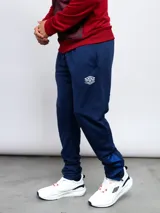 Pantalón de entrenamiento azul marino con logo de Umbro en blanco, corte ajustado y detalles en azul brillante en los tobillos.