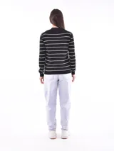 Cárdigan negro con rayas horizontales blancas, cuello en V y botones dorados.