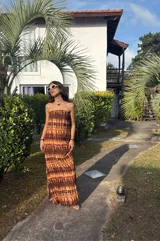 Vestido strapless largo con estampado batik en tonos marrones y beige, entallado al cuerpo y con espalda baja descubierta.