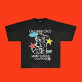 Remera negra de corte boxy con estampa de un personaje de historieta con gorra, dados y estrellas. Incluye texto "Gurises Club", "Uruguay", "Montevideo Cool Kids" y el logo de la marca Kaboa.