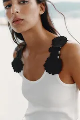 Top blanco de algodón con escote redondo y tirantes decorados con apliques de flores negras.
