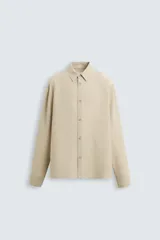 Camisa de manga larga color celeste claro, con cuello solapa y cierre frontal de botonadura. Presenta una textura sutil en el tejido.