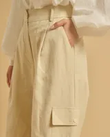 Pantalón acampanado color beige con pinzas, bolsillos italianos y bolsillos de parche con solapas en los laterales. Cierre con botones y cintura con trabillas.
