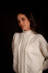 Sweater color crudo con cuello alto y diseño trenzado.